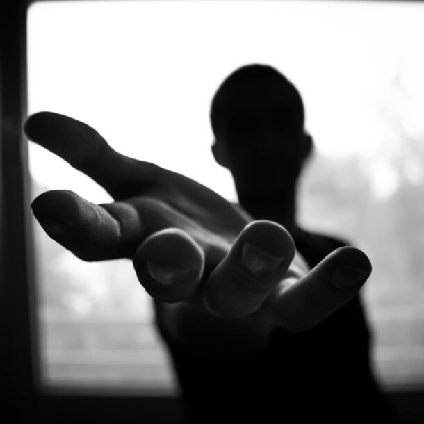 Silhouette of a hand reaching out in a black and white contrast.